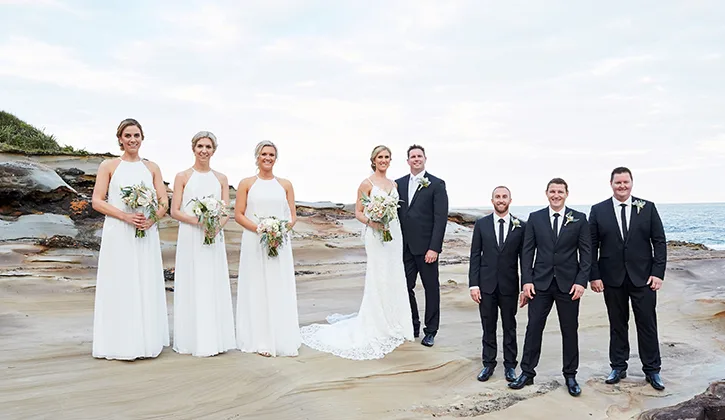 Wedding party standing on the rocks by the ocean