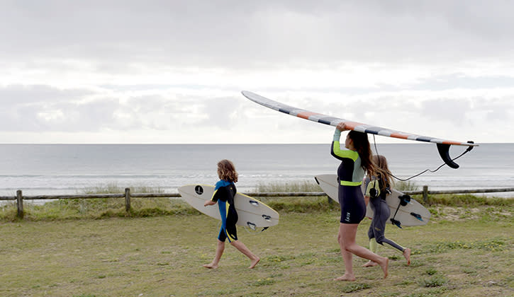 Family walking to beach with surf boards