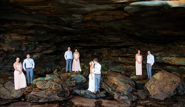 Aerial view of wedding party standing in pairs on the rocks at night
