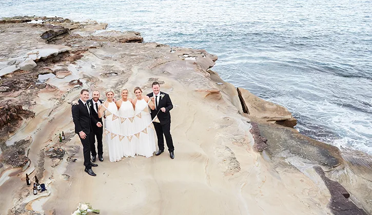 Aerial view of wedding party on the rocks by the ocean