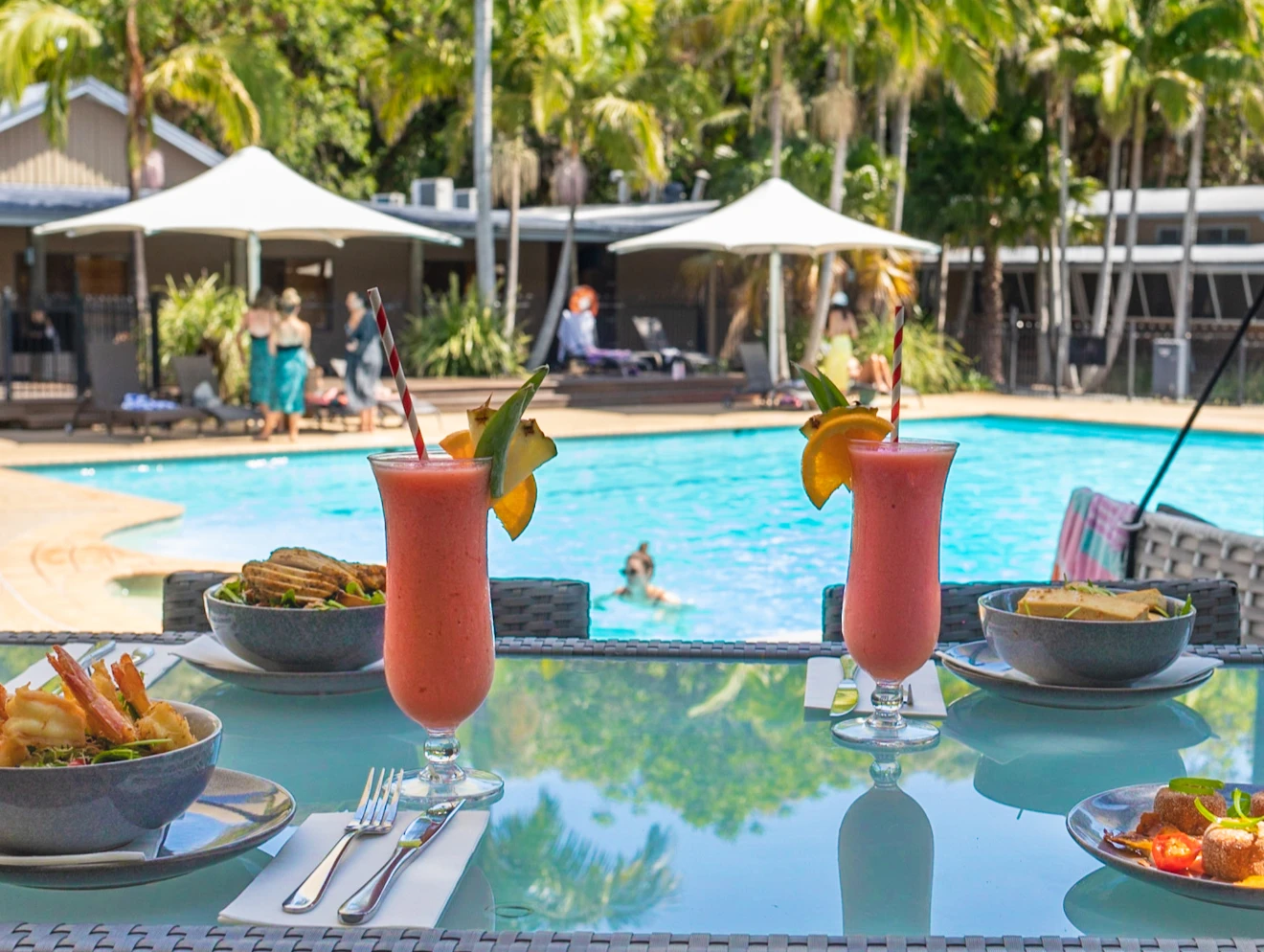 Cocktails and food on a poolside table