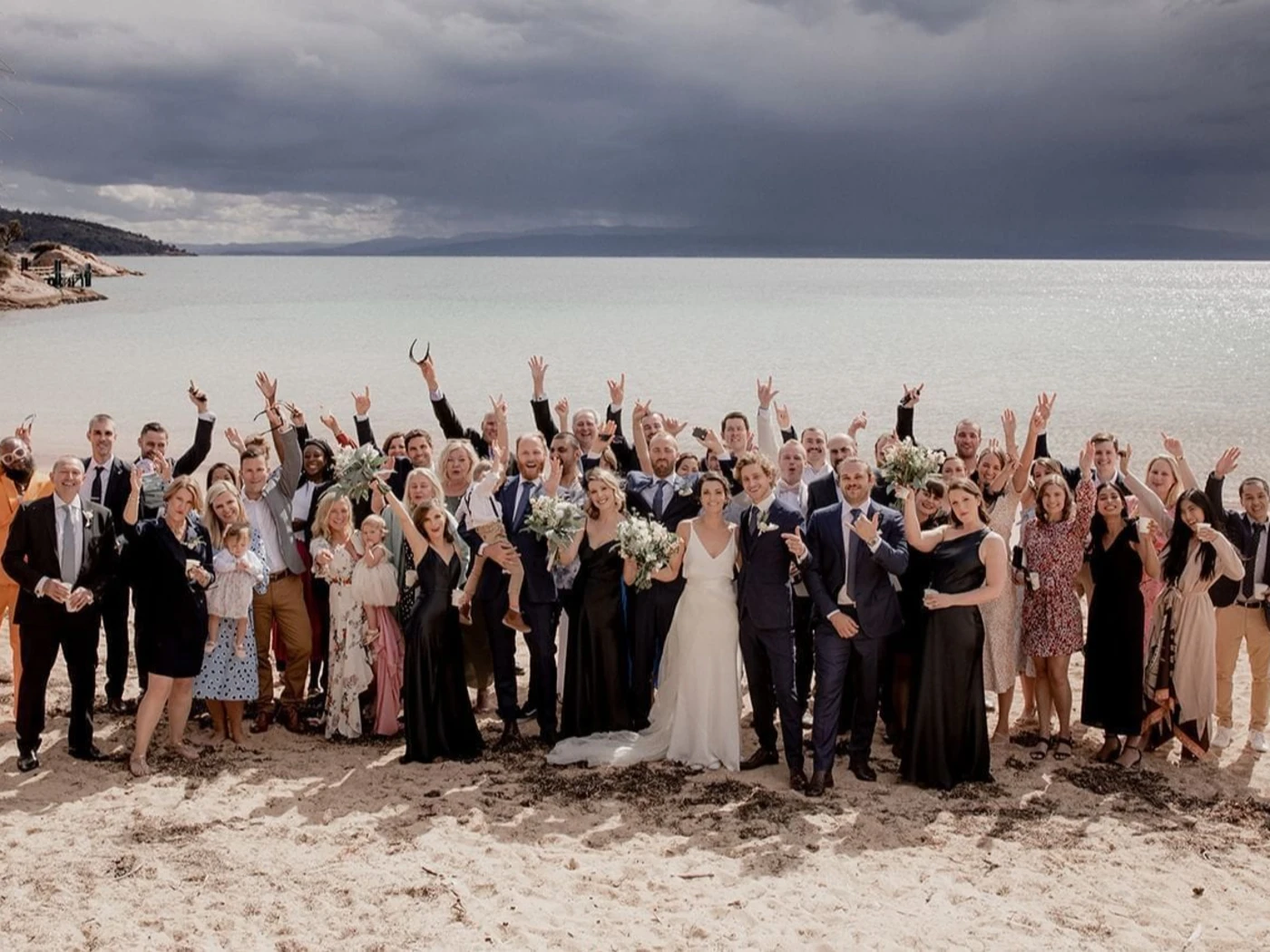 The wedding party posing on the Beach on a sunny day at Freycinet Lodge