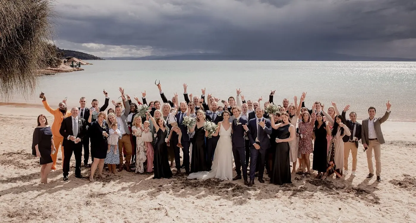 The wedding party posing on the Beach on a sunny day at Freycinet Lodge