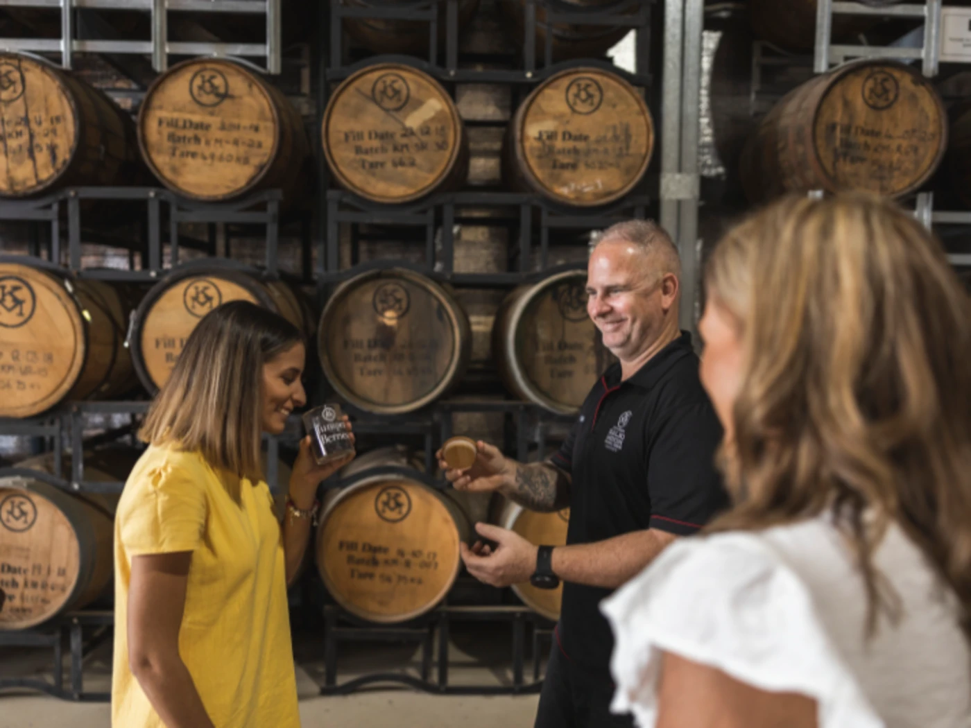 Woman smelling sample at the Kalki Moon Distillery with wine barrels in the background