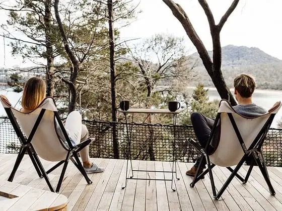 Couple lounging & drinking hot beverages while overlooking the Lake at Freycinet Lodge