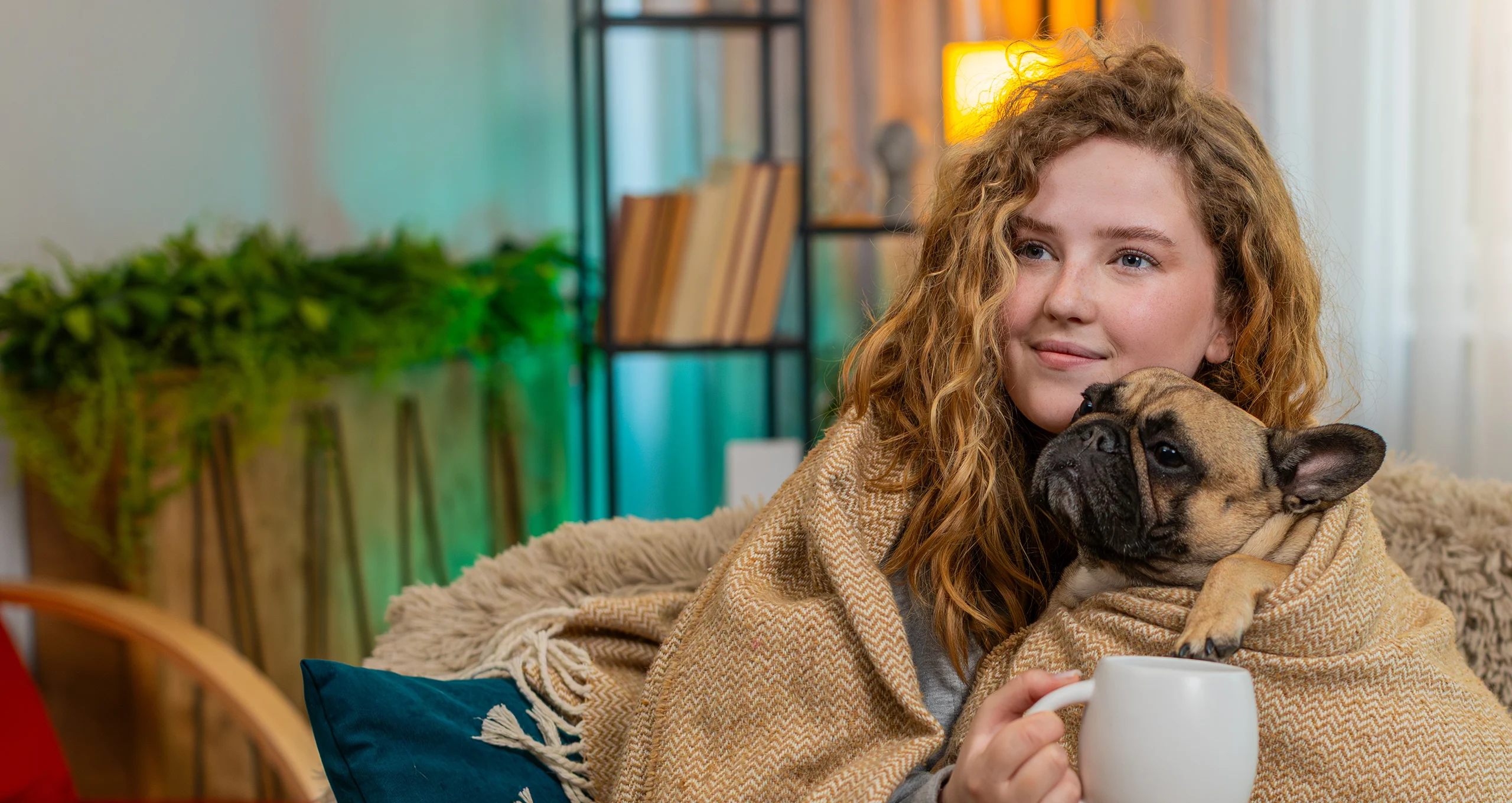 h woman snuggled on couch having tea with pug