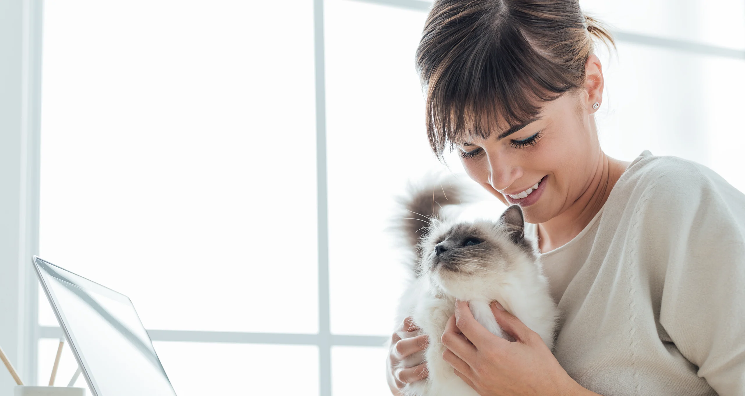 h woman holding cat next to computer