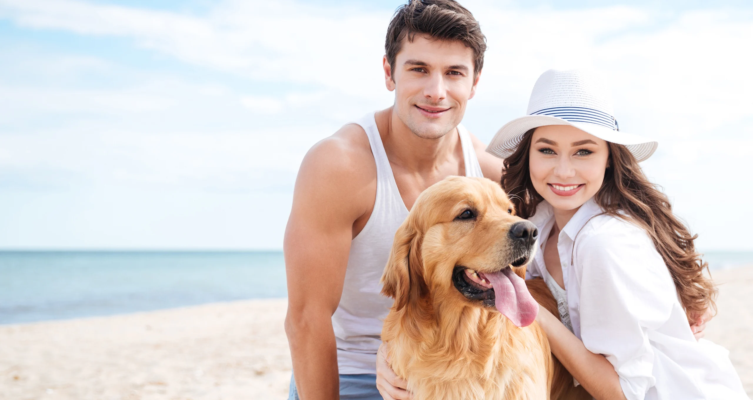 h man and woman with golden retriever on beach