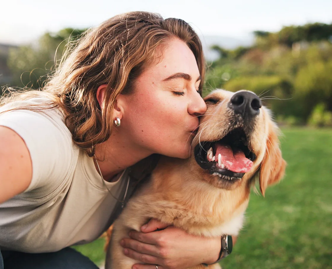 woman kissing muzzle of yellow lab
