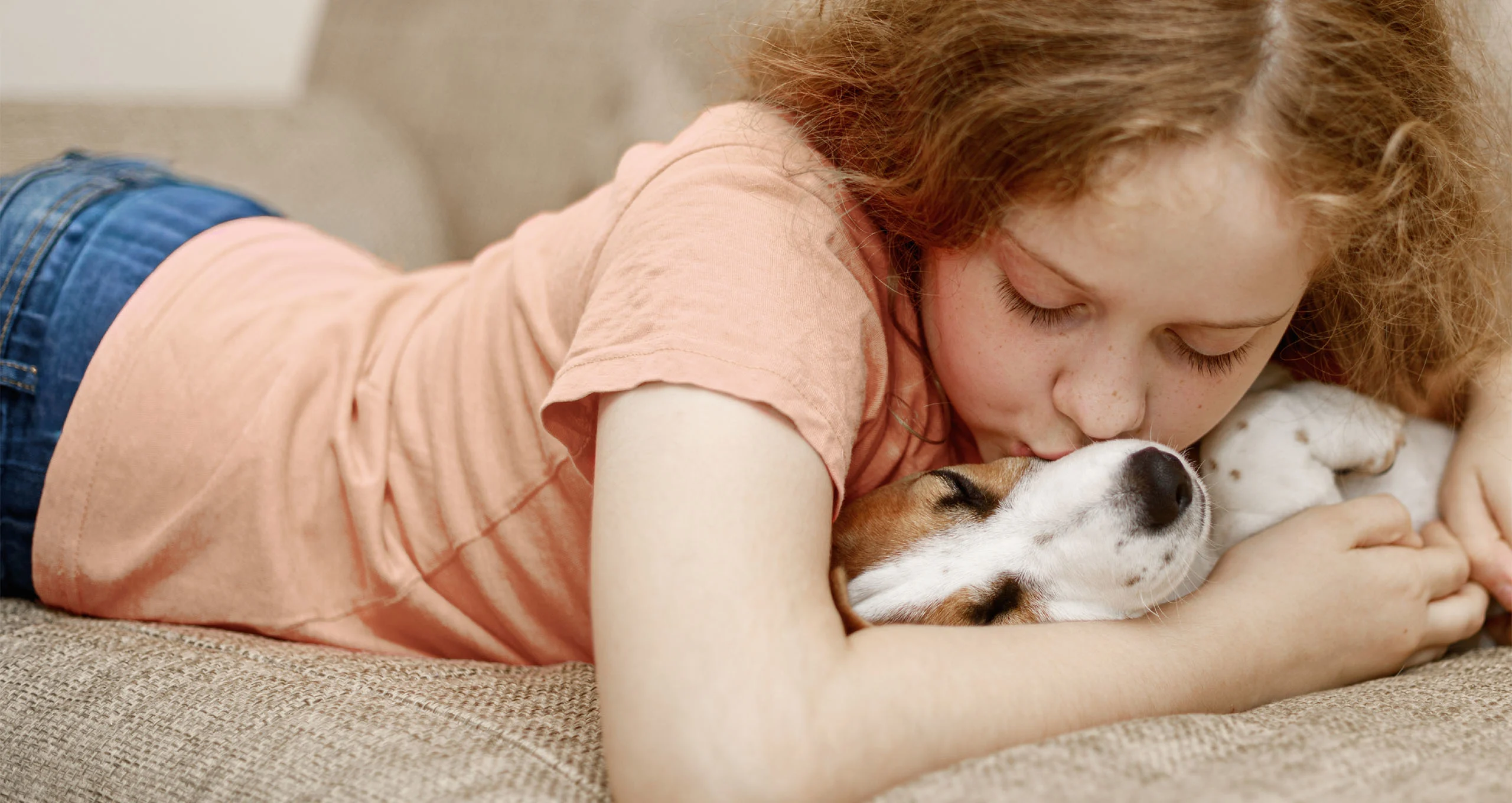 h curly haired girl kissing muzzle of dog upside down in her arms