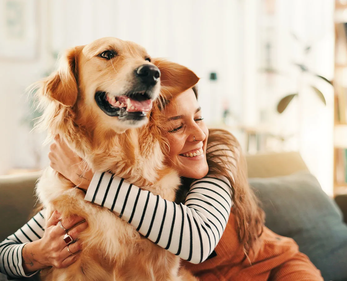 woman in striped shirt hugs retriever on couch