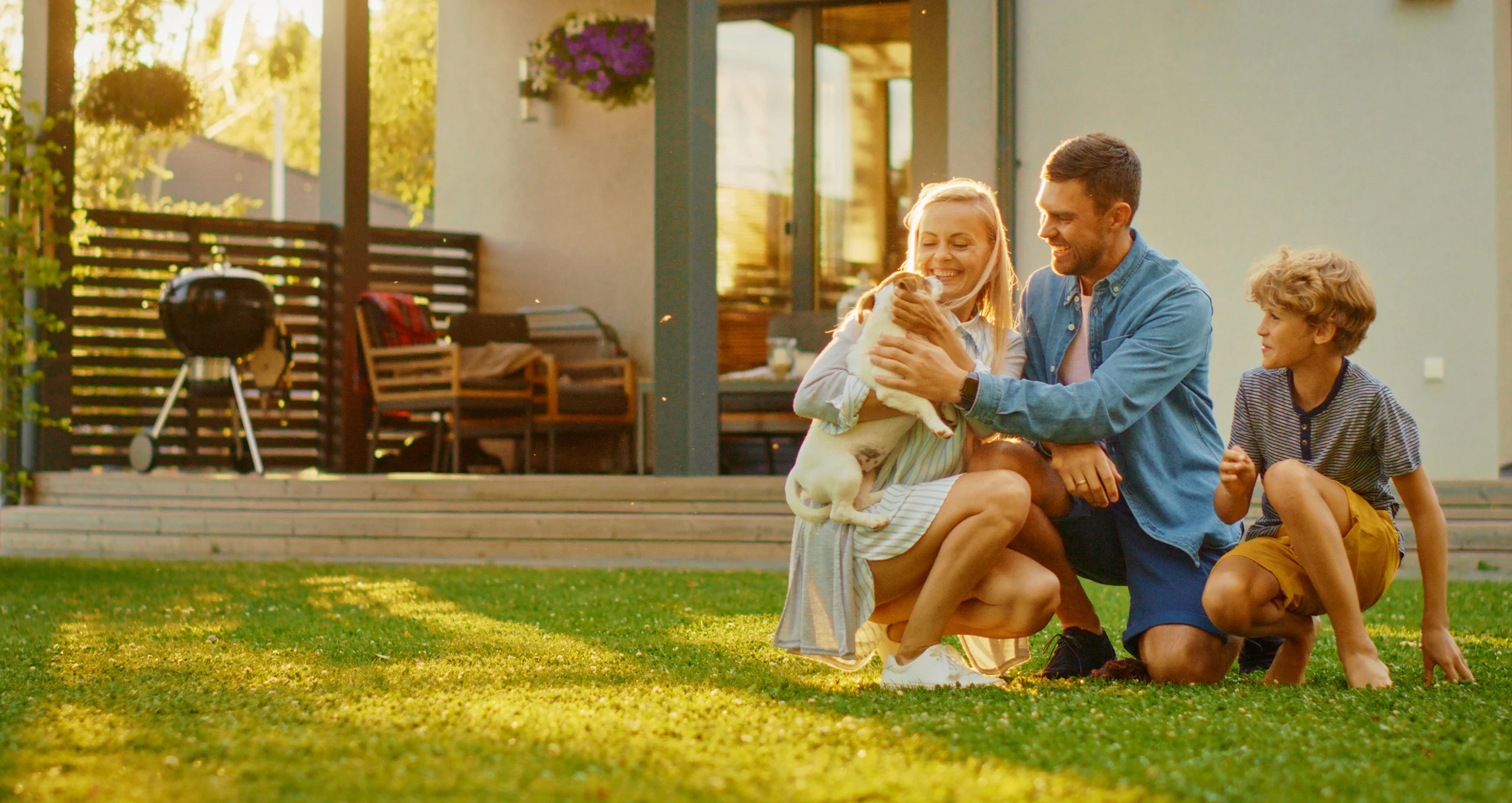 h family kneeling outside with small dog in backyard