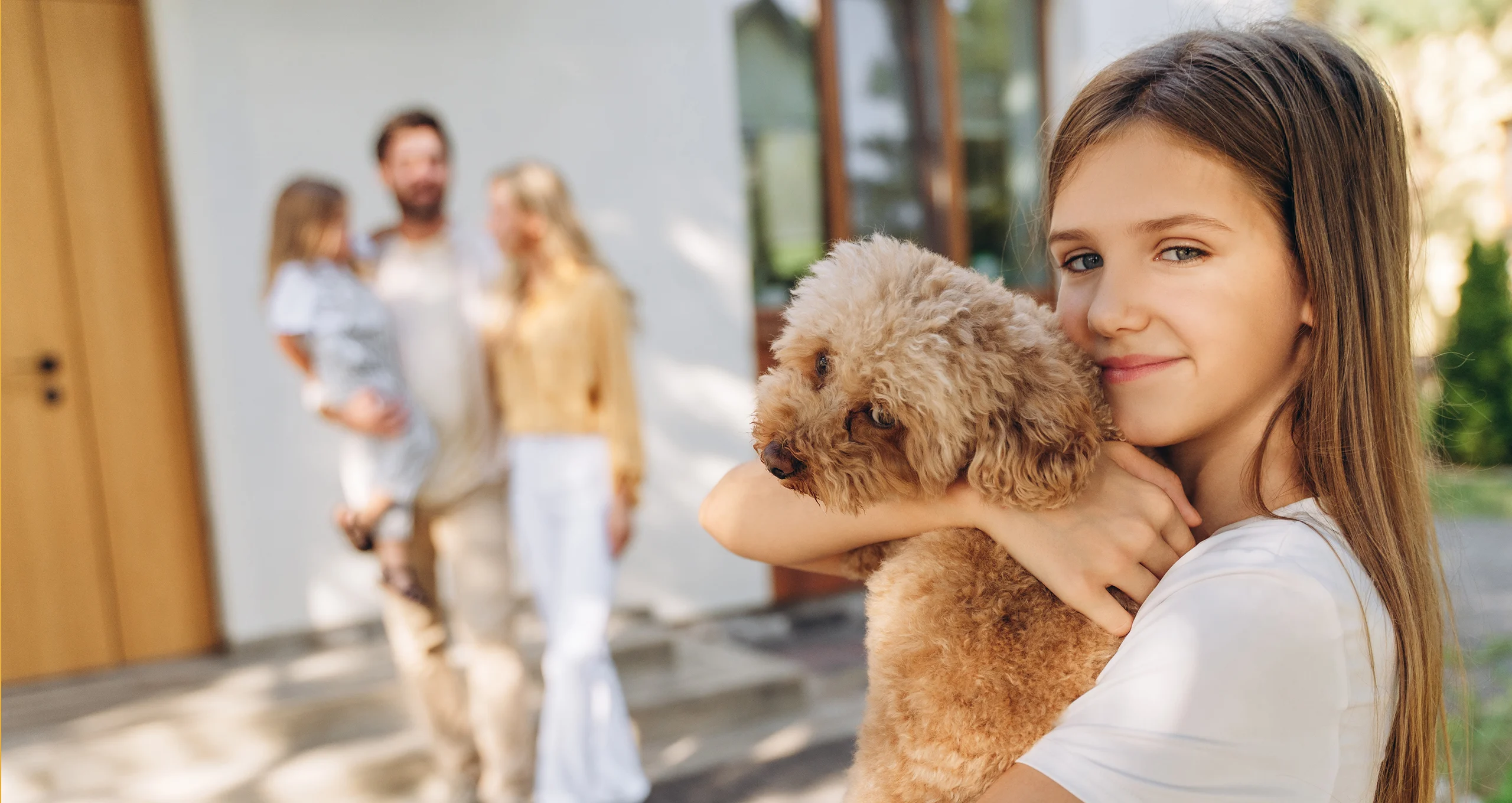h girl hugging poodle outside house