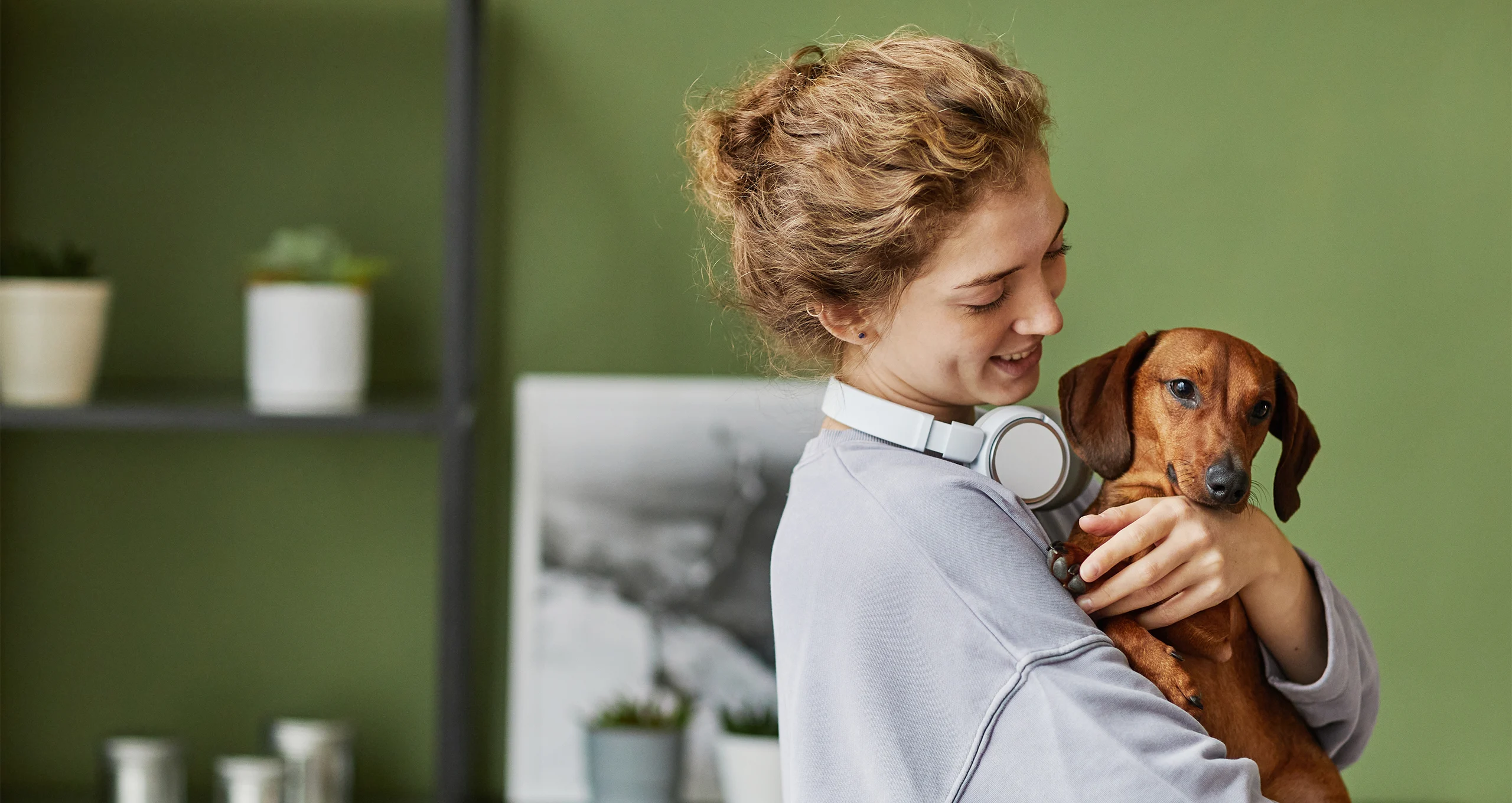 h girl with headphones around neck holding a dachshund