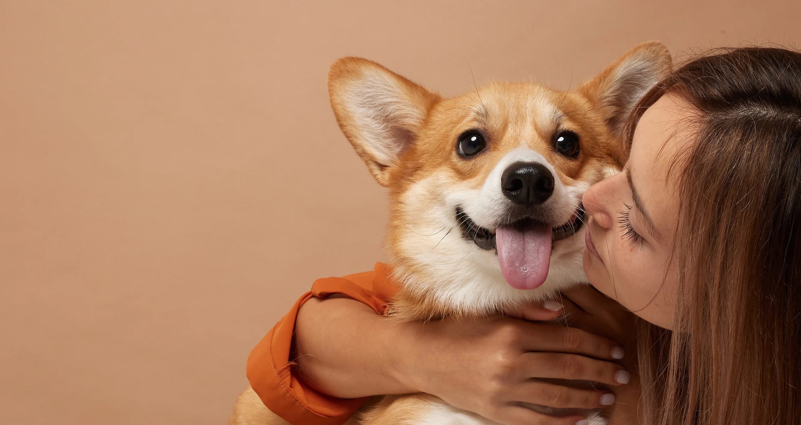 h woman kissing muzzle of corgi