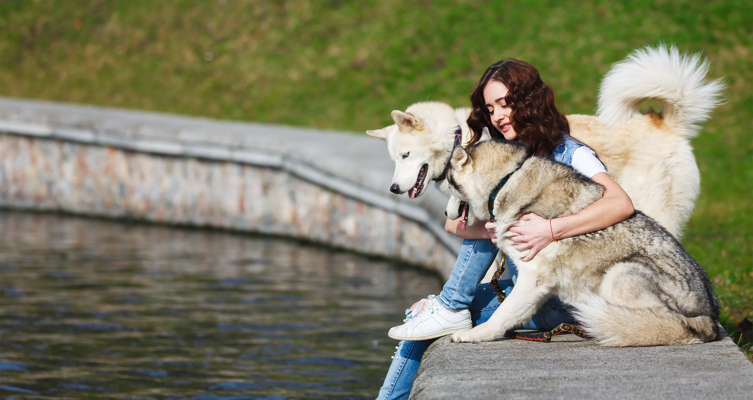 girl with huskies near water embankment