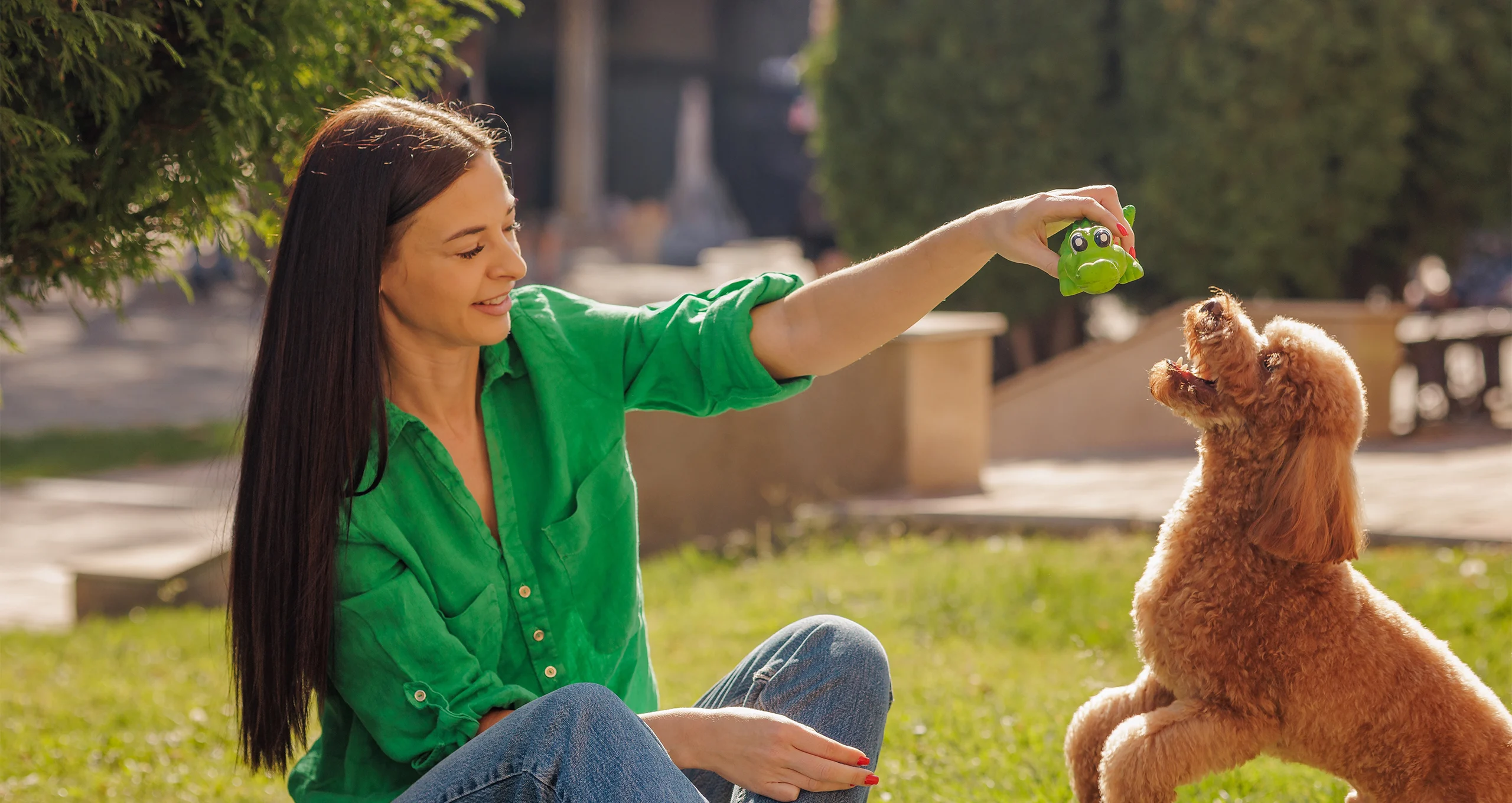 h woman in green shirt plays without poodle outdoors