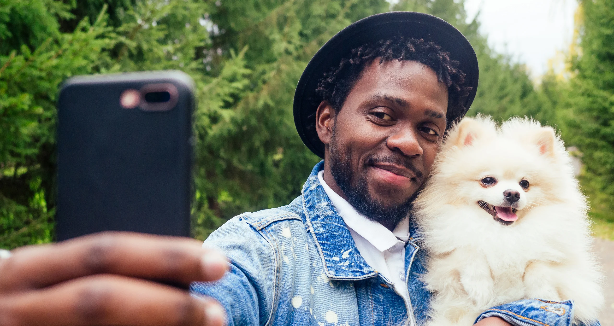h denim jacket wearing man with whote dog taking a selfie