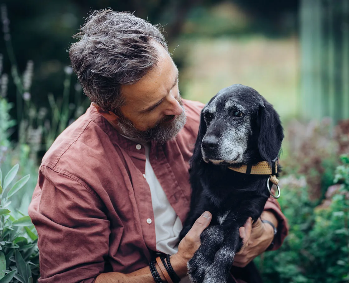 older man with elder dog outside