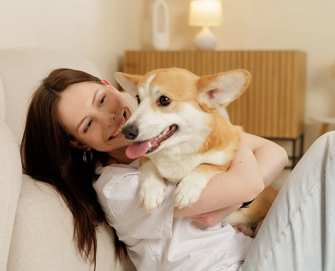 woman smiles with pembroke corgi