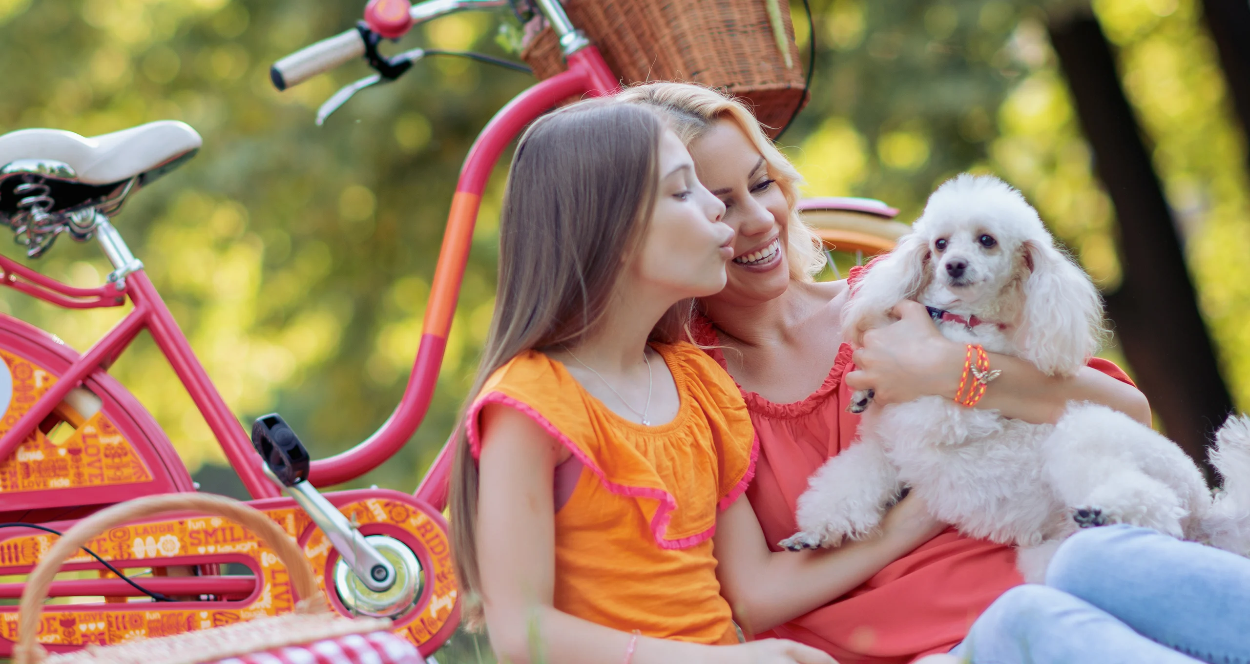 h woman and girl with white poodle on picnic with bike