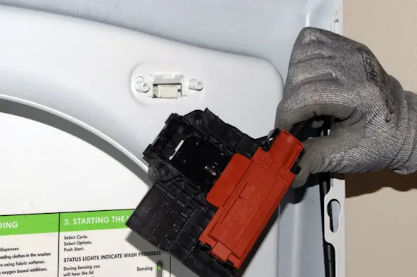 PHOTO: Release the lid switch/lock assembly from the top panel.