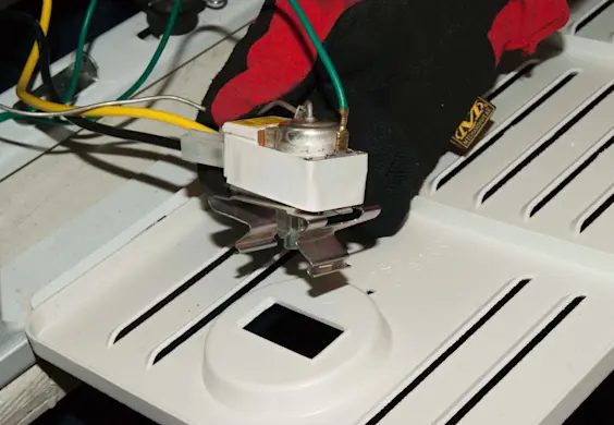 PHOTO: Release the thermostat from the grille cover.