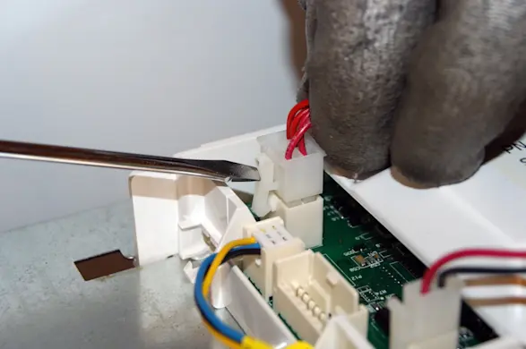 PHOTO: Release the locking tabs on the control board wire harness connectors.