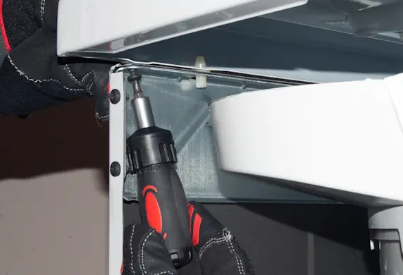 PHOTO: Remove the screw from under the left front corner of the top panel.