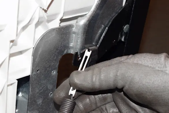 PHOTO: Remove the tension spring from the door hinge.