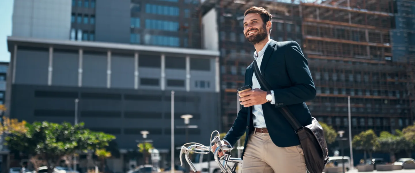 Man walkling on a street with bicycle and a cup of coffee