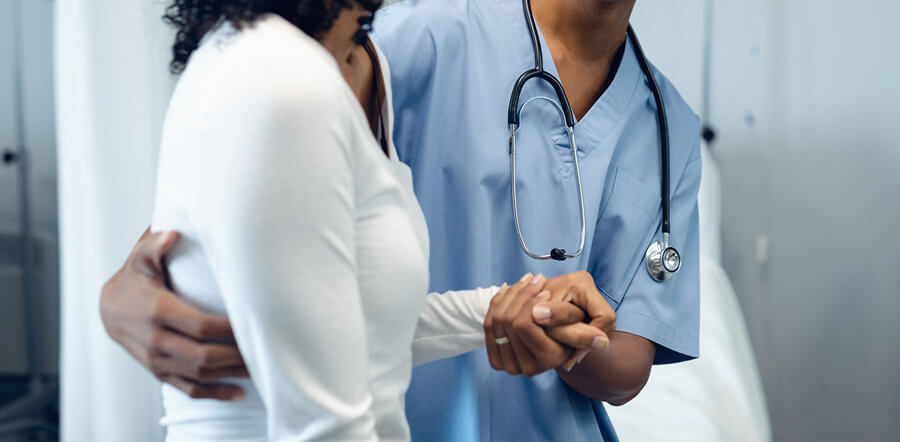 Profesional sanitario dándole la  mano a una paciente para ayudarla.