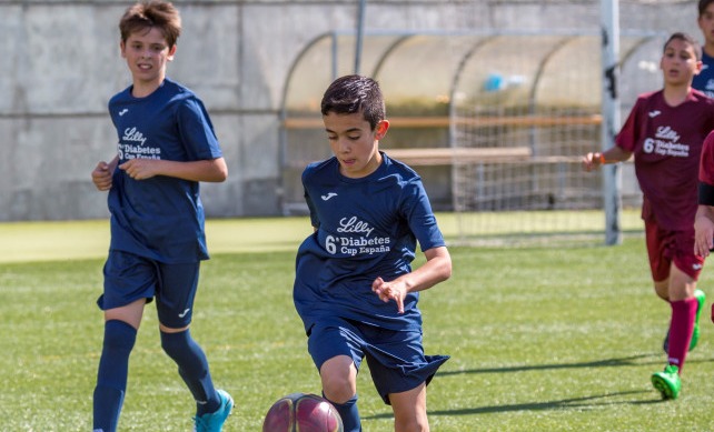 Niños jugando a fútbol en un campo verde
