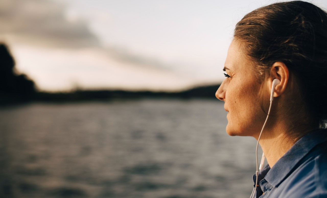 Mujer morena de perfil mirando al horizonte con el mar de fondo
