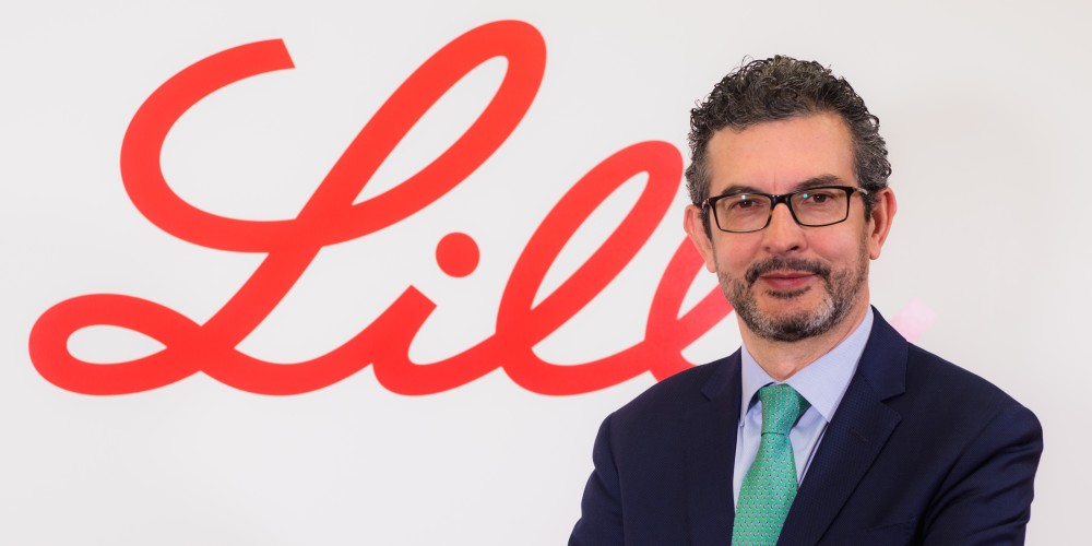 Hombre con traje de chaqueta delante del logotipo de Lilly
