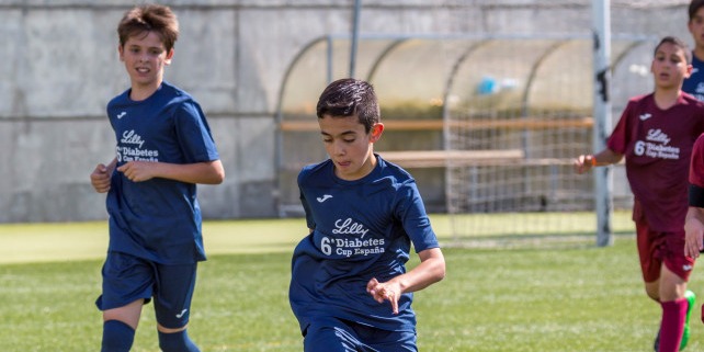 Niños jugando a fútbol en un campo verde
