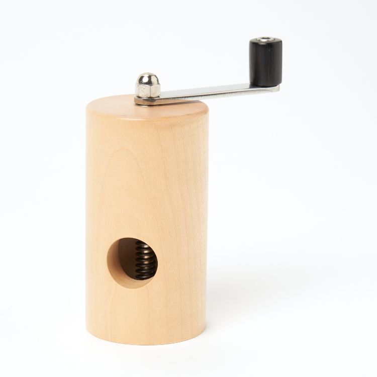 A pale wooden cylinder with a hole in the side for the nut. On the top there is a stainless steel handle with an ebony top that can rotate the inside mechanism to grind the nut.