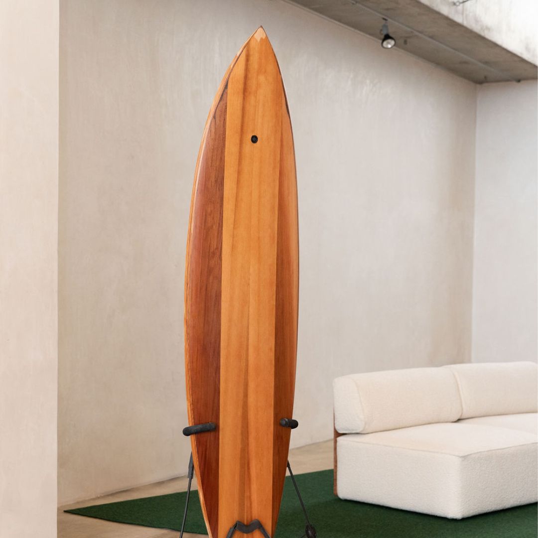 A timber surfboard on a black display frame
