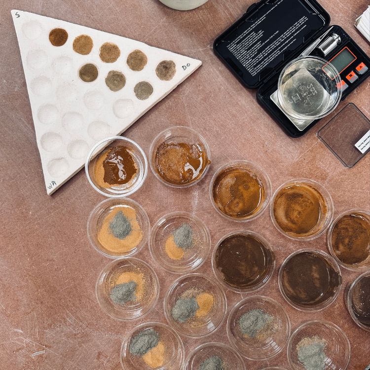 A triangular plate with small indentations for testing glazes. Small clear glass bowls with glaze materials.
