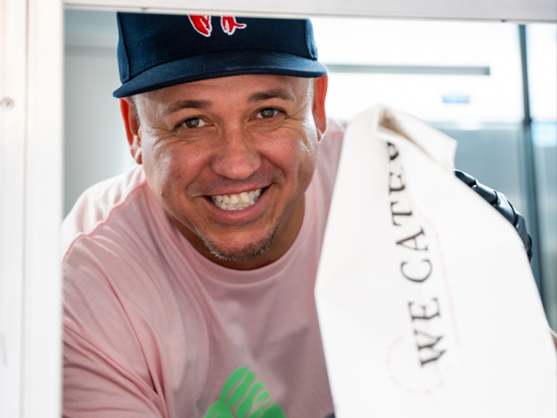 Local Owner, Damon Cole serves a bag of food out of the Truck window. 