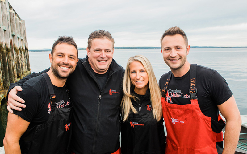 A photo of our Charlotte owners posing in fishing gear with Cousins Maine Lobster founders Jim & Sabin.