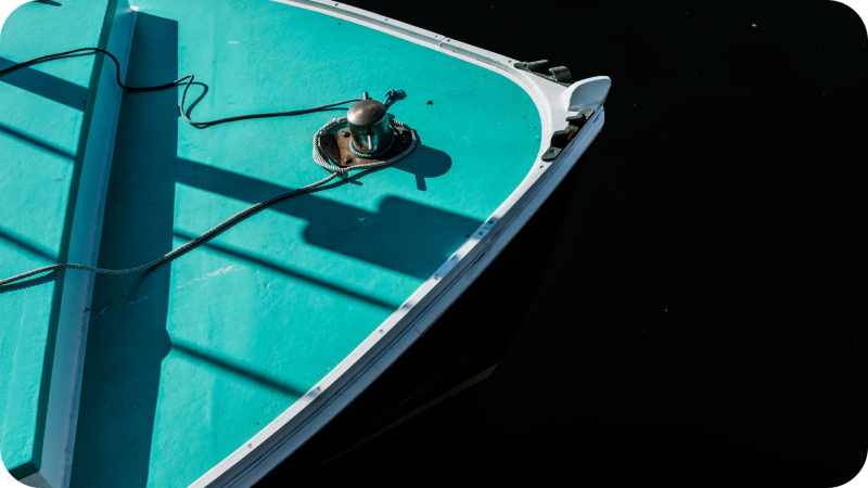 A pretty image of just the bow of a bright turquoise painted lobster boat.