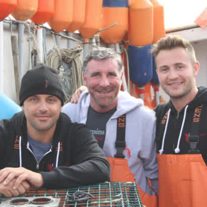 A photo of our former Nashville franchisee, standing on a lobster boat in Maine, with Cousins Jim & Sabin.
