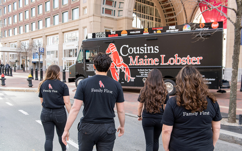 A photo of our Boston family taken from behind, as they walk towards their food truck.  Our slogan 
