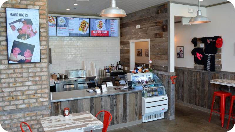 An image of the interior of our Neptune Beach restaurant showing the front of house area with digital signage and ordering counter.