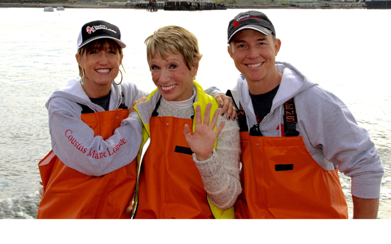 A photo of our Raleigh franchisees sitting with their arms around Barbara Corcoran, all dressed in fishing gear in Maine.