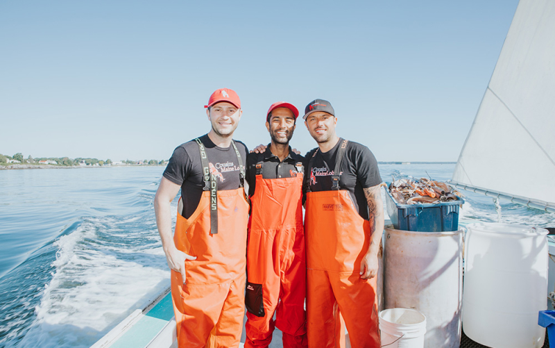 A photo of our Orange County owner posing with Cousins Jim & Sabin near the back of a lobster boat in Maine.