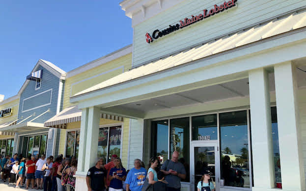 A group of people stands outside a Cousins Maine Lobster restaurant in Neptune Beach, Florida.
