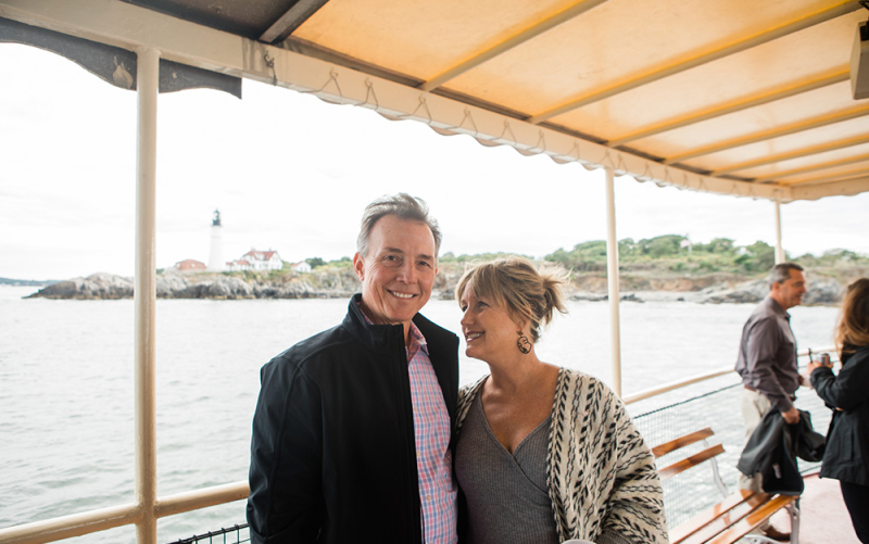 A photo of our Raleigh franchisees enjoying a scenic boat cruise in Maine with the Portland Head Light in the distance.