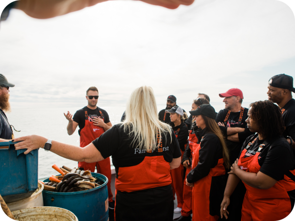 An image of Cousins Maine Lobster family members on a boat in Maine, listening to Cousin Jim speak as they are out training and fishing.